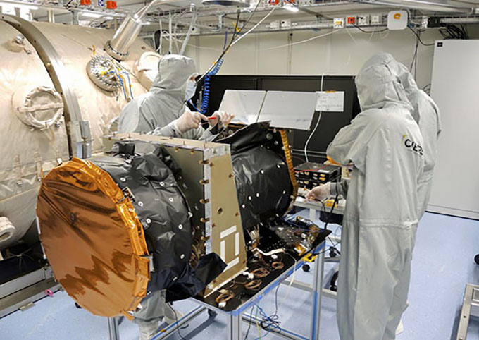 The CHEOPS telescope in the clean room at the University of Bern. Employees wear a protective suit with mask.